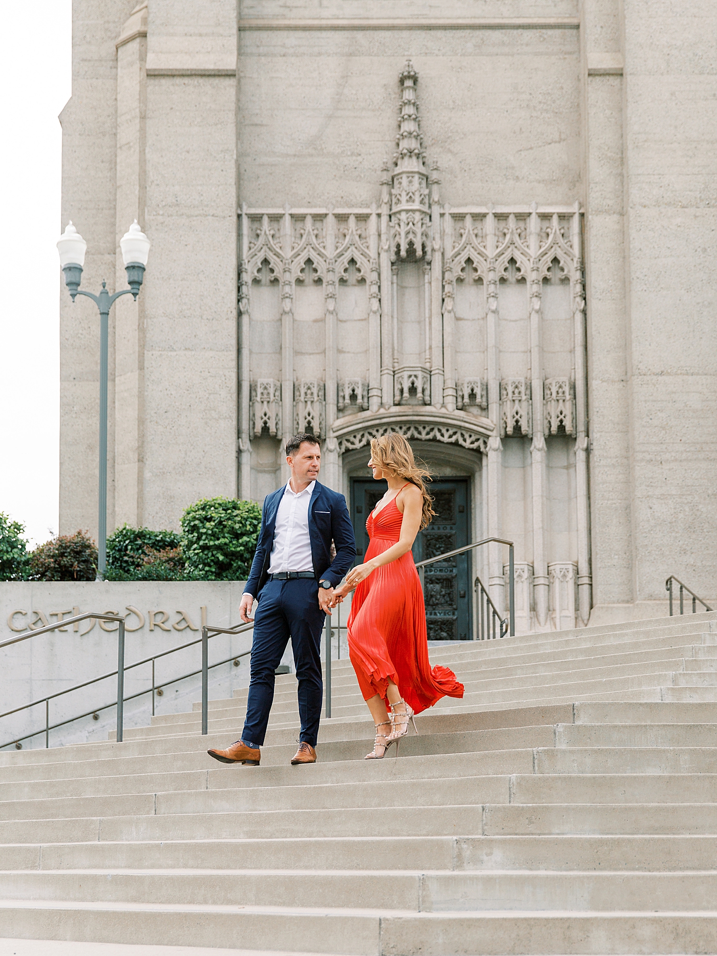 Couple in red and blue walking down the steps at a church | Photo by Diane Sotero