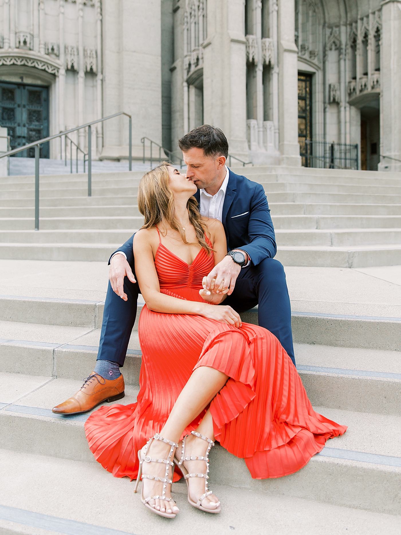 Woman in red dress kissing her fiancé | Photo by Diane Sotero