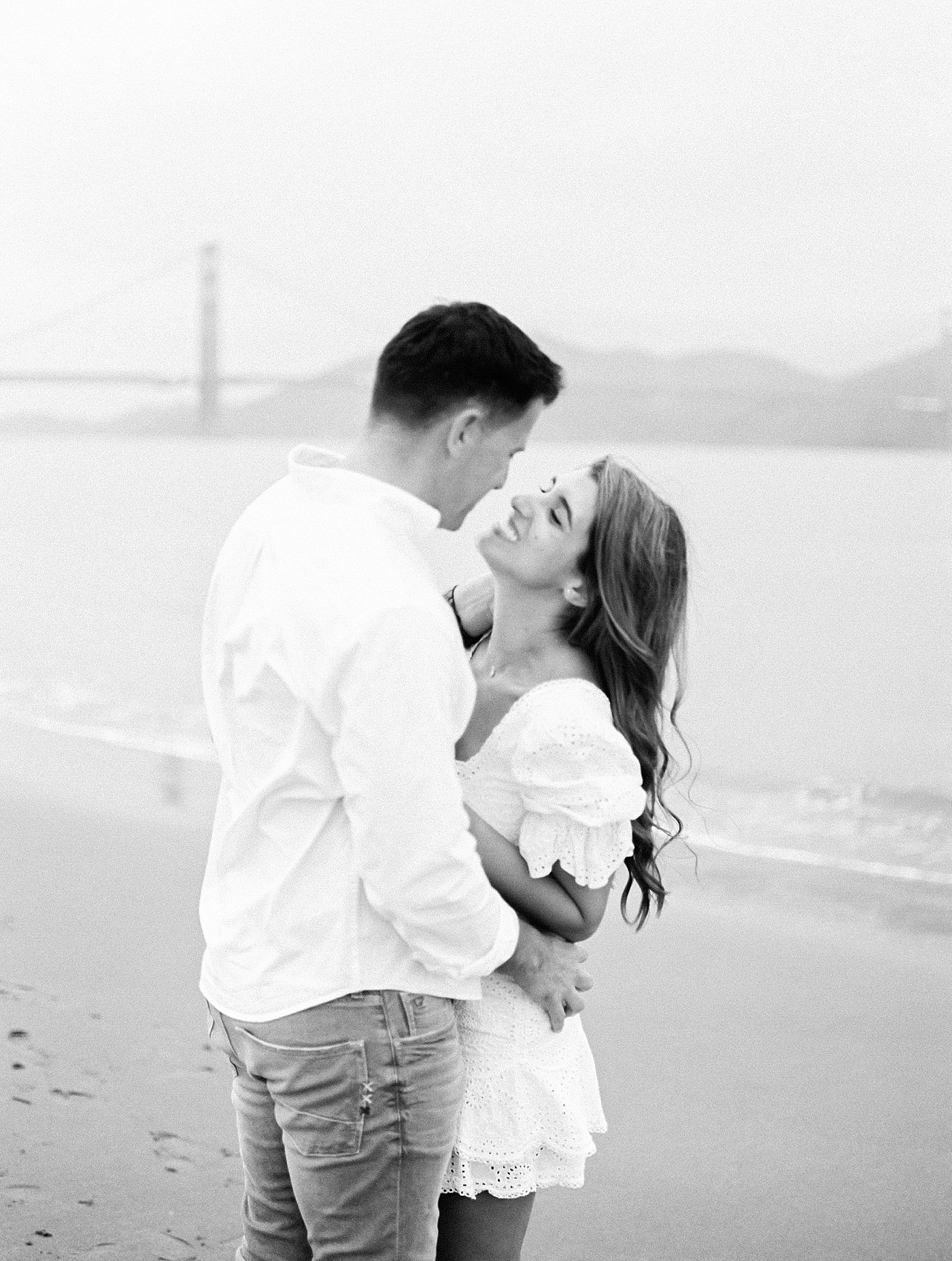 Black and white image of couple embracing on the beach near San Francisco | Photo by Diane Sotero