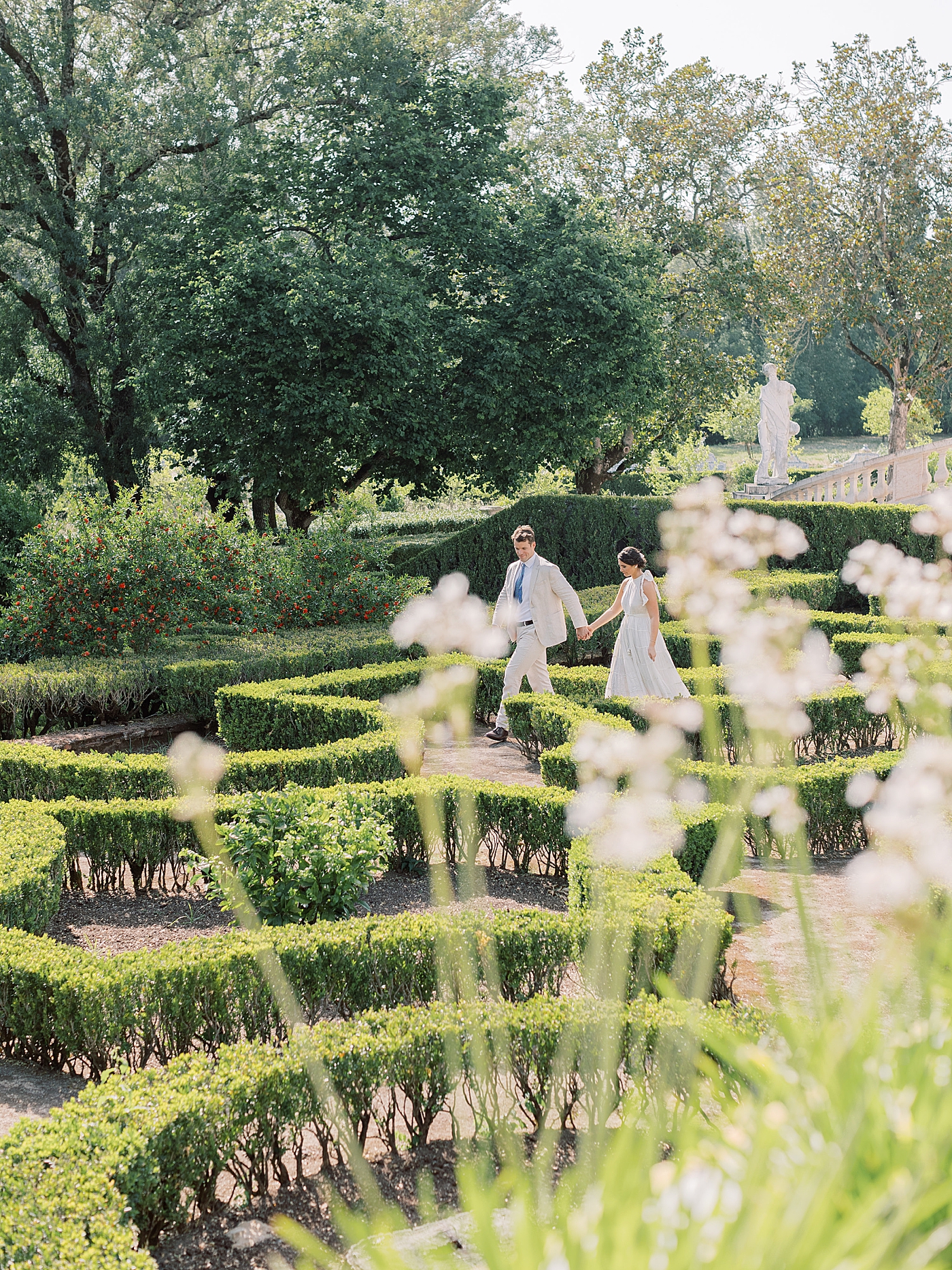 Couple walking hand in hand through a garden at Palacio de Queluz | Photo by Diane Sotero 