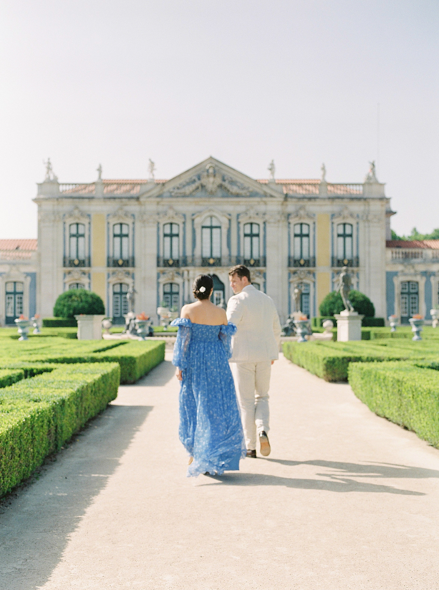 Couple holding hands walking toward Palacio de Queluz | Photo by Diane Sotero 