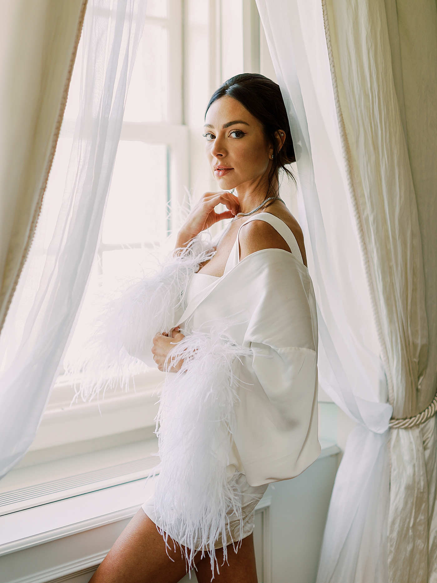 Bride in a robe looking out the window | Image by Diane Sotero Photography