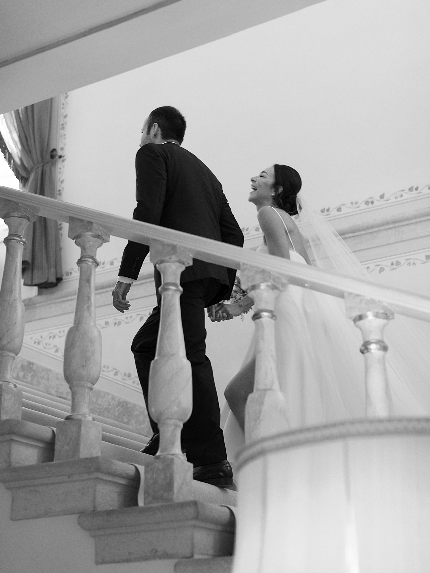 Black and white image of bride and groom walking up stairs | Image by Diane Sotero Photography