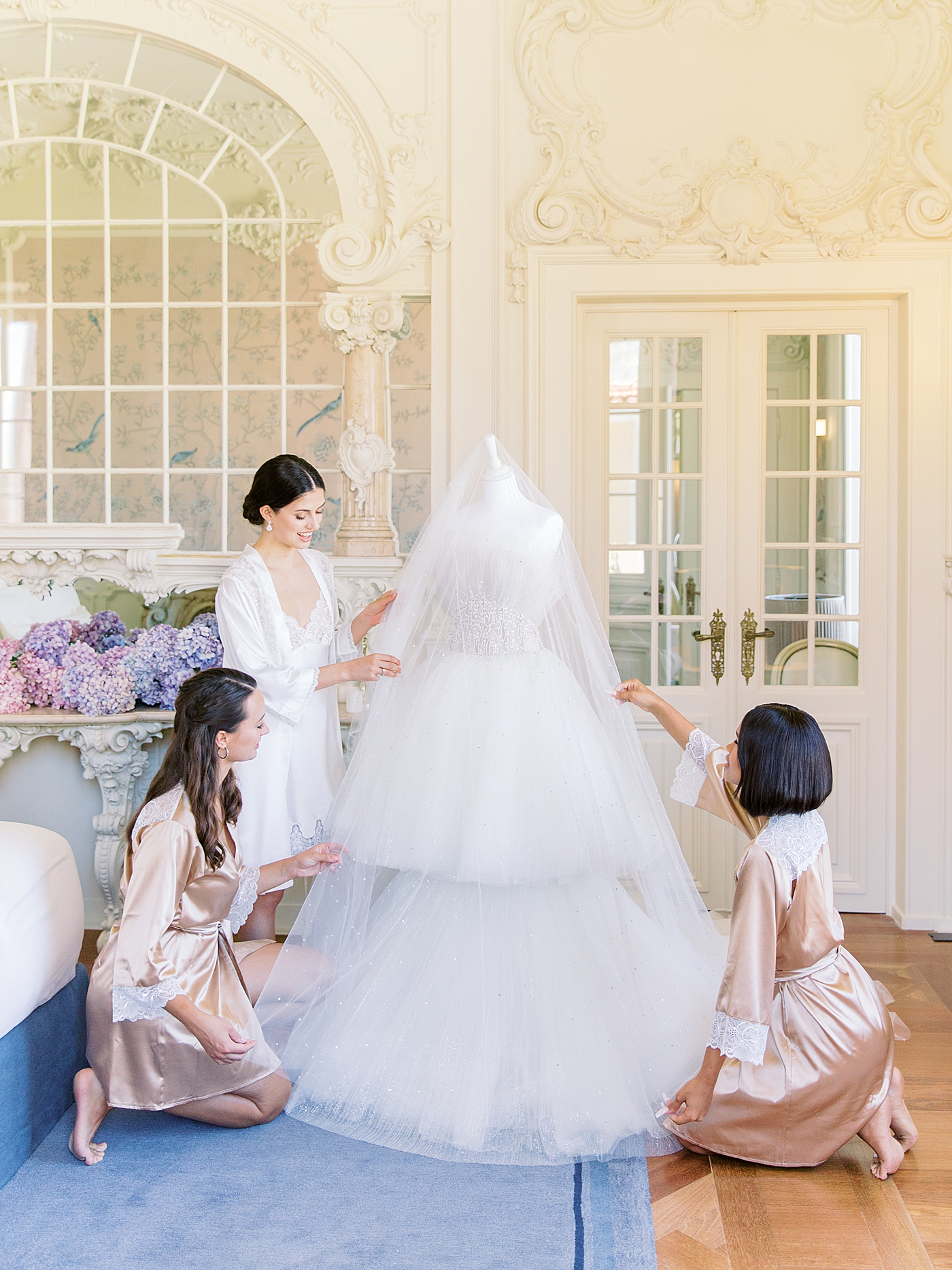 Bride and bridesmaids adjusting brides dress in getting ready room | Image by Diane Sotero 
