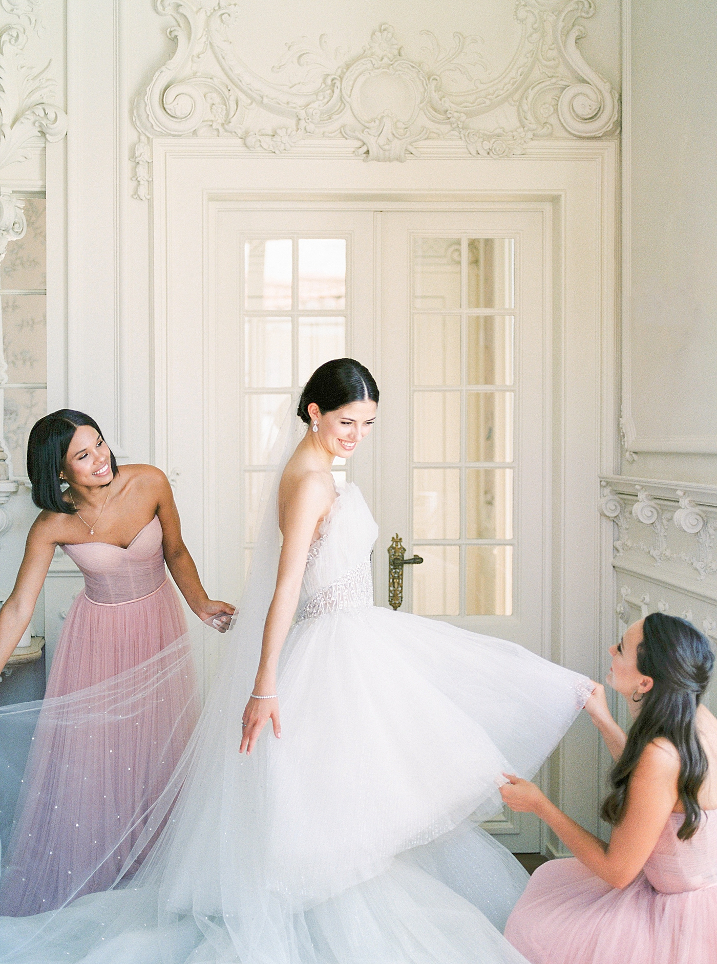 Bridesmaids adjusting brides gown in her getting ready room | Image by Diane Sotero 